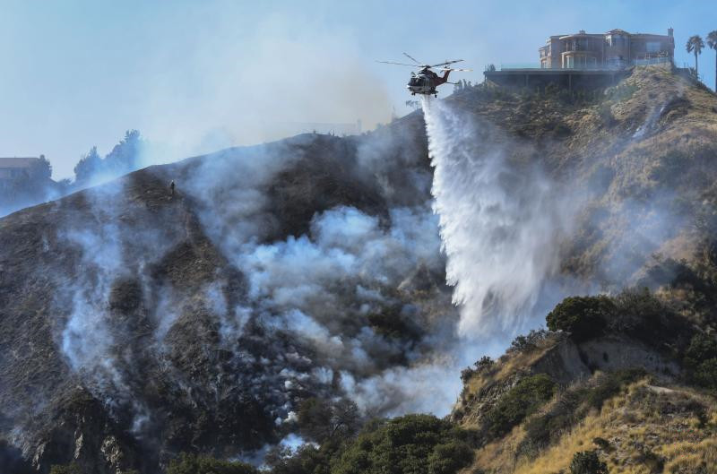 由于连日高温，加州洛杉矶县伯班克市突发山火，一架直升机到场洒水灭火。（新华社）.jpg