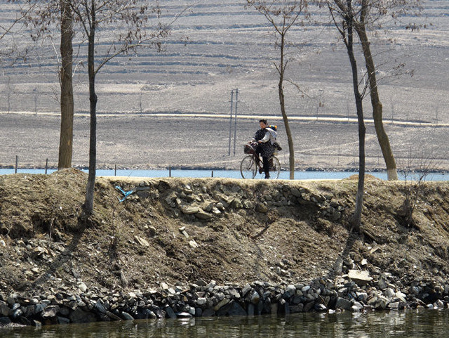 乡间小道骑着自行车的朝鲜妇女。.jpg